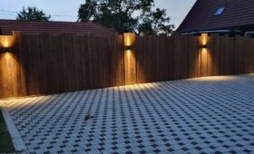 Habillage bois d'un mur avec des lames de terrasse brunes et intégration de 4 lampes design