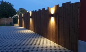 Habillage bois d'un mur avec des lames de terrasse brunes et intégration de 4 lampes design