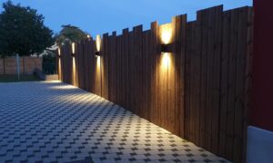 Habillage bois d'un mur avec des lames de terrasse brunes et intégration de 4 lampes design